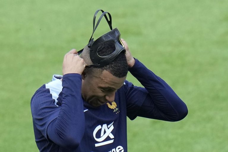 Penyerang Perancis, Kylian Mbappe, memperbaiki letak masker wajahnya saat berlatih di Padeborn, Jerman, Kamis